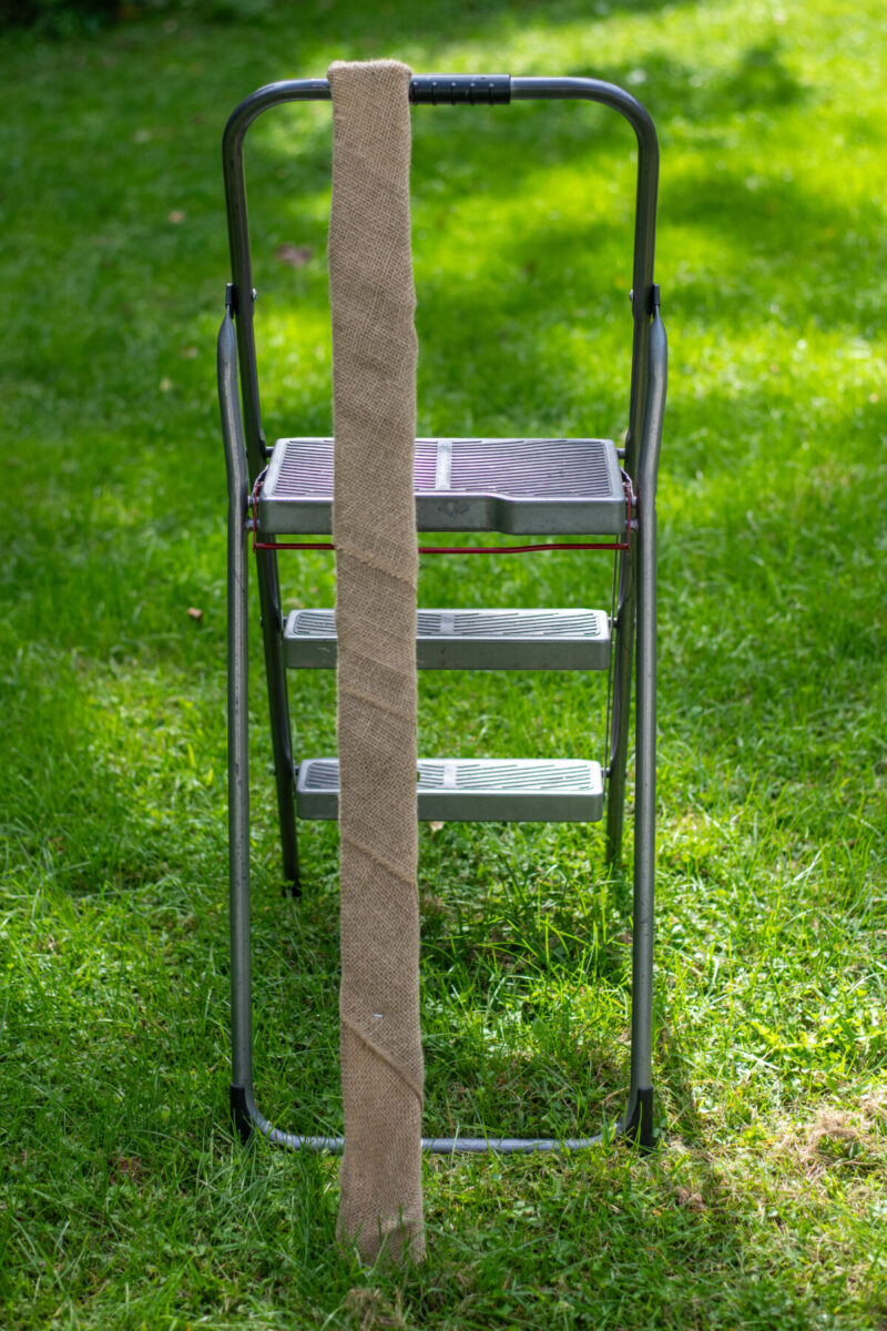 Burlap covered 2"x3" leaning against ladder