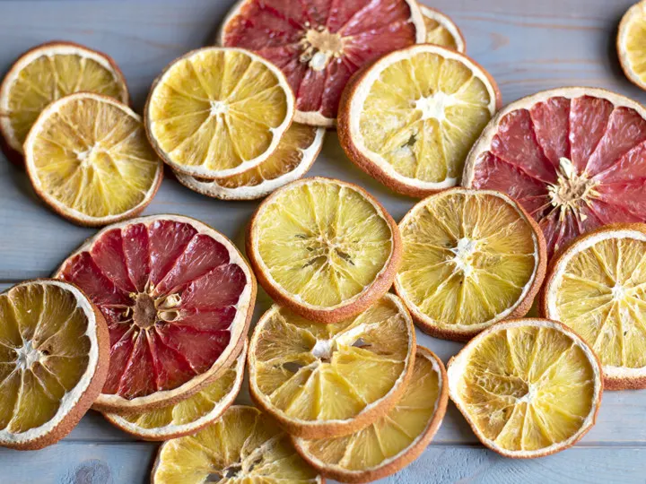 Several citrus slices are spread out on a wooden background.